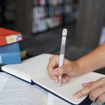 Two hands hold down a journal while one of them is positioned over a lined piece of paper with the Chocolate Chip Cookie Pen Diffuser.