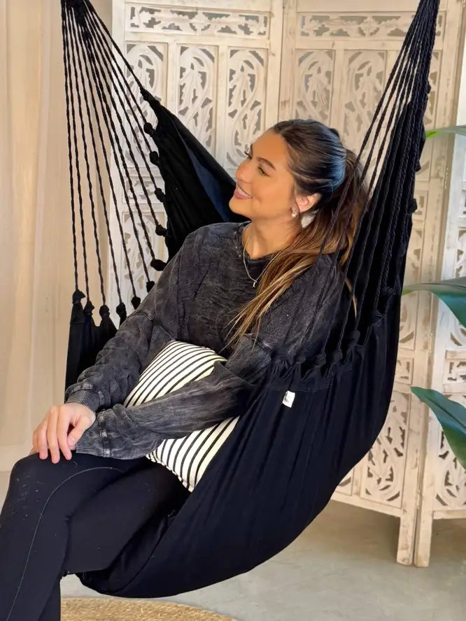 A woman relaxes in the Black Boho Hammock Chair Swing.