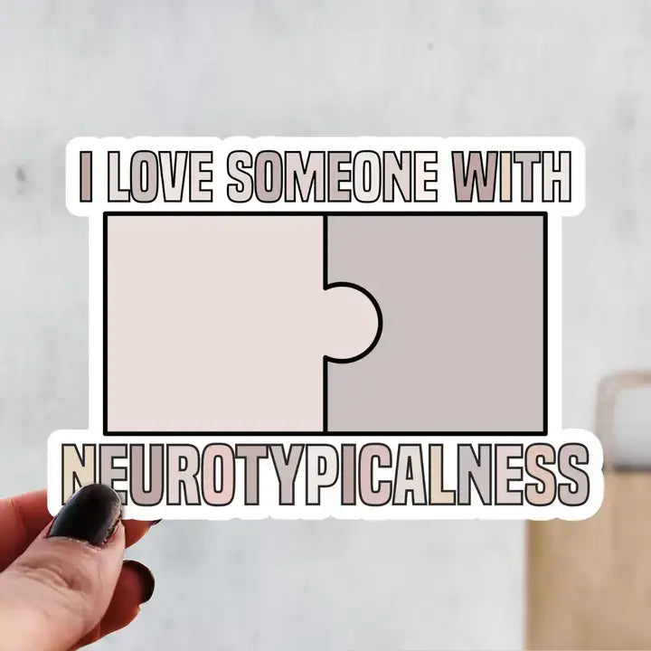 A hand holds a sticker that reads: I Love Someone With Neurotypicalness.
