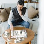 A senior sits at a coffee table and plays with the Match the Dots Dominoes.