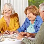 Three seniors sit at a table and organize the dominoes in Match the Dots.