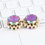 Two oil slick Mini Cog Fidgets next to each other on a keyboard.