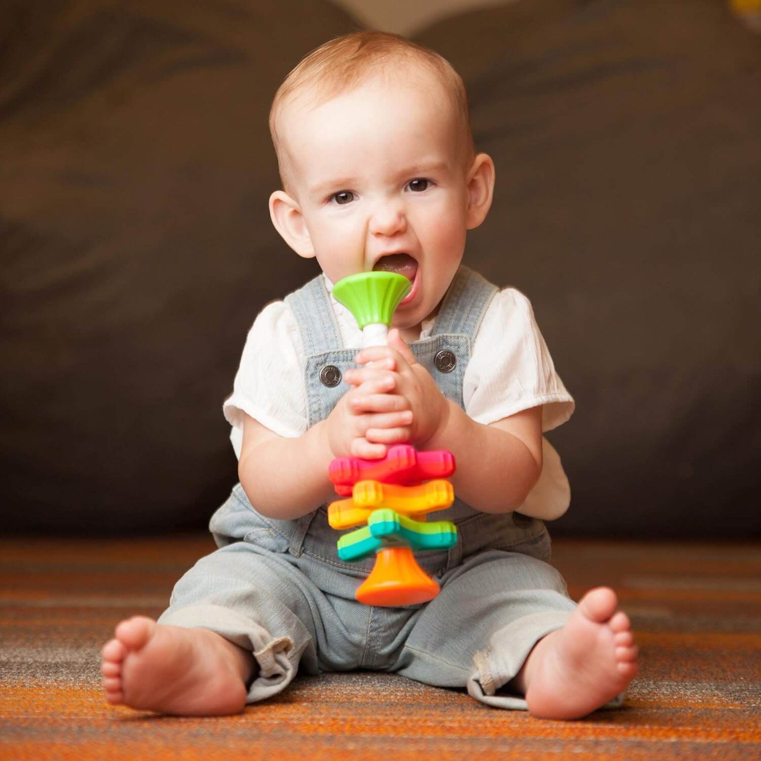 A baby puts the MiniSpinny up to their mouth.