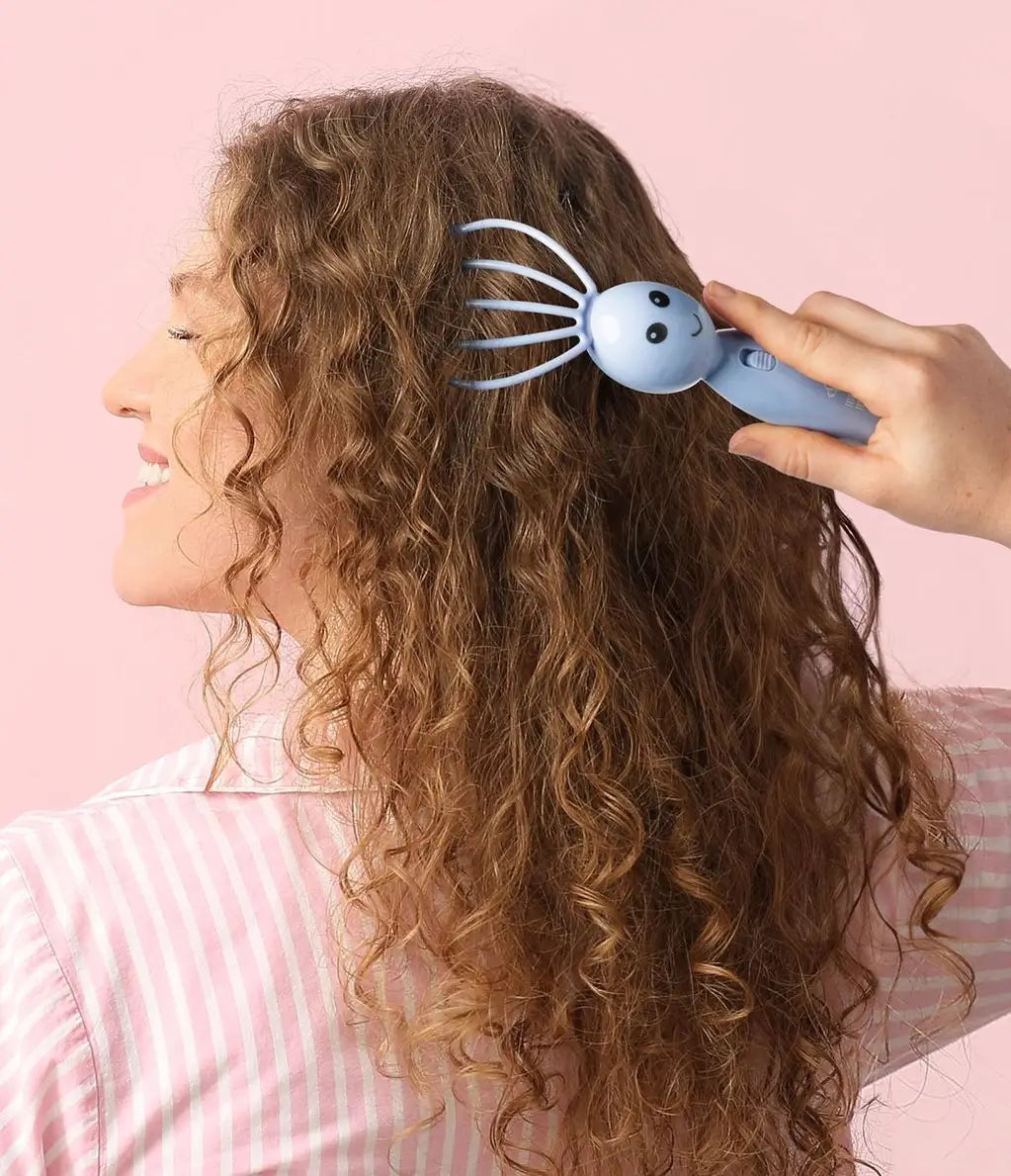 Someone pulls the light blue Modern Monkey Shrimp Scalpi Head Massager through their long brown hair.