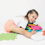 A child leans over a pile of the pieces from the Medium 1 Sensory Playmat Set.