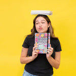 Someone balances several sticker books on their head while making a funny face and holding up theCommitment Issues - Colorful Reusable Sticker Book.