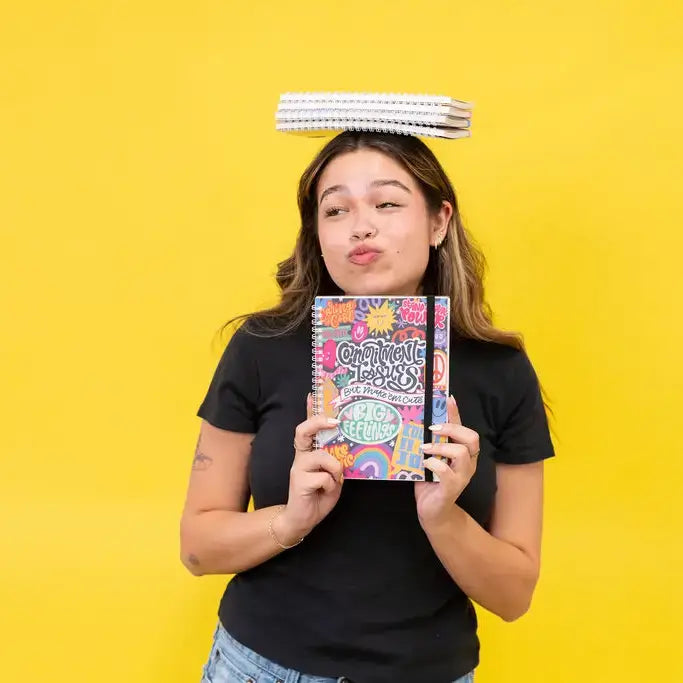 Someone balances several sticker books on their head while making a funny face and holding up theCommitment Issues - Colorful Reusable Sticker Book.