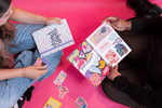 Two people look through their own sticker collections in the Sticker Party Album.