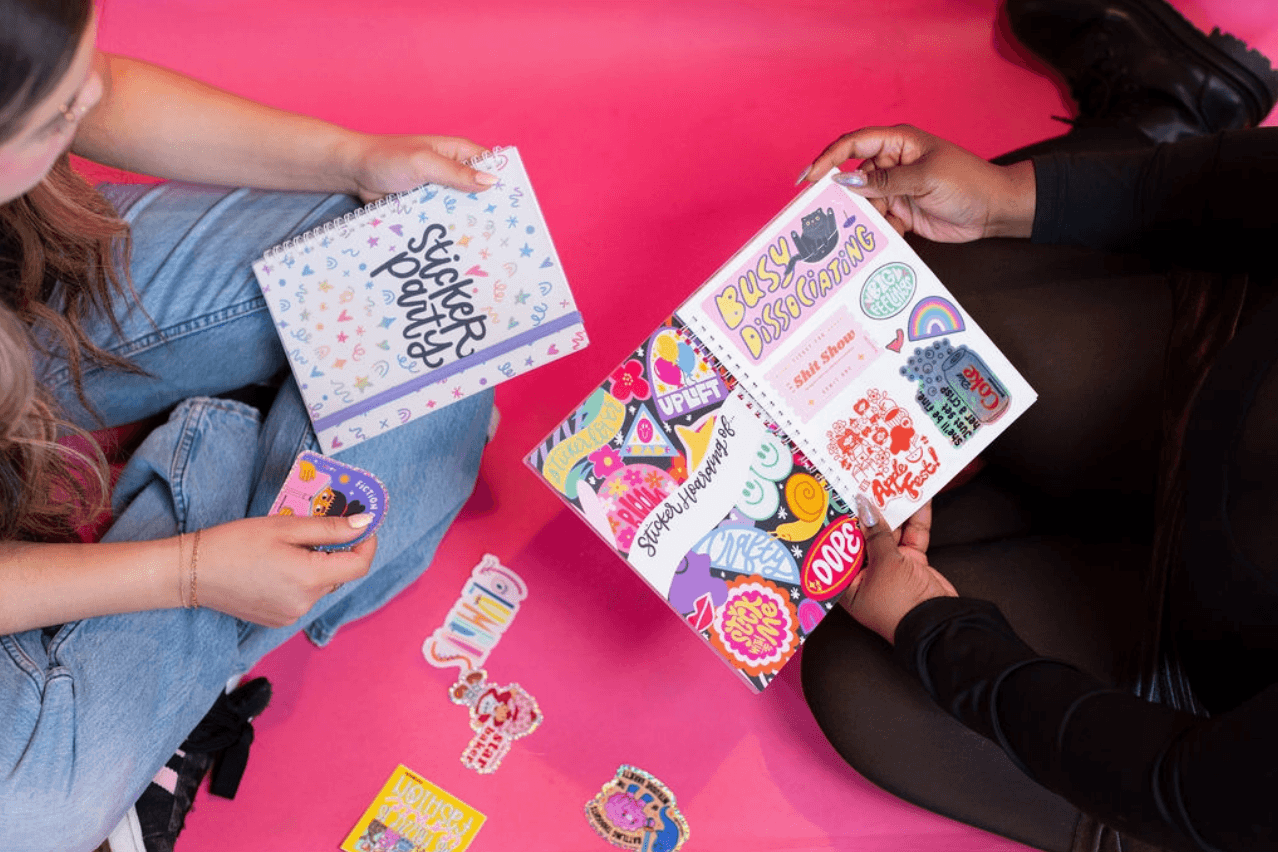 Two people look through their own sticker collections in the Sticker Party Album.