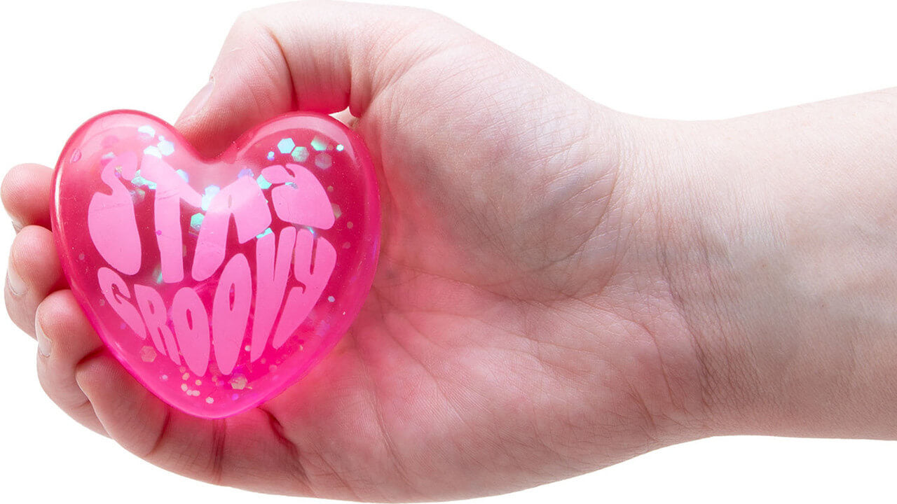 A hand holds a pink NeeDoh Good Vibes Only that says "Stay Groovy."