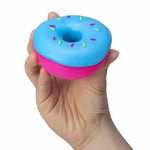 A hand holds the blue NeeDoh Dohnut.