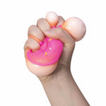 A hand squishes the pink NeeDoh Dohnut.