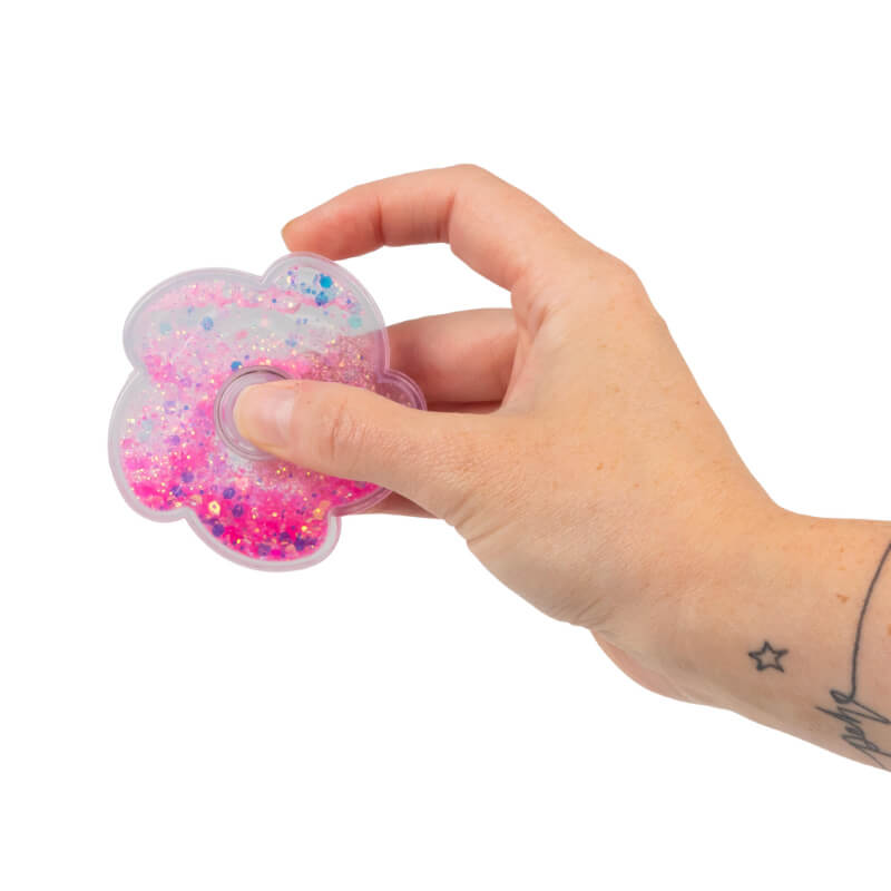A hand holds a Liquid Glitter Fidget Spinner with the glitter shifted towards the bottom.