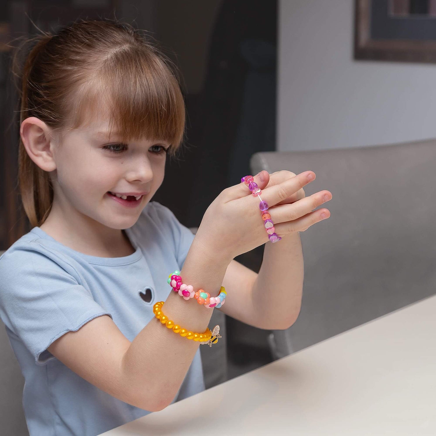 A child puts on the bracelet made from beads in the Pick N Pop Bracelet - Love Heart Edition.