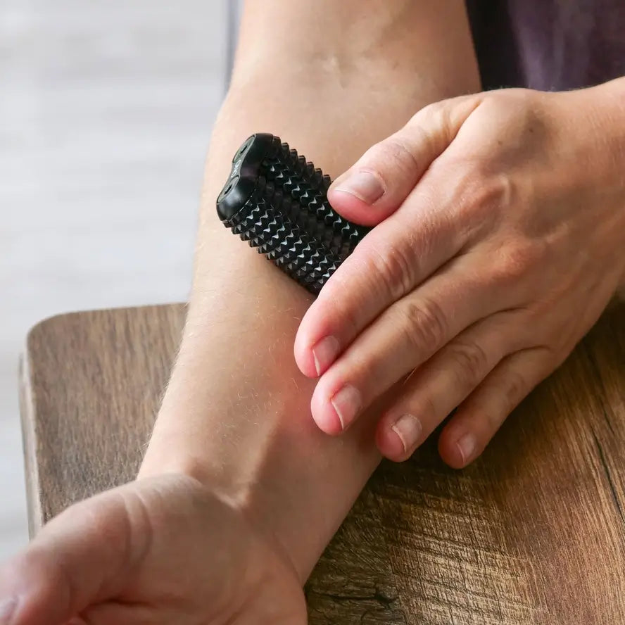 A hand holds the full size Ono Aluminum  Acupressure Roller up against a forearm.
