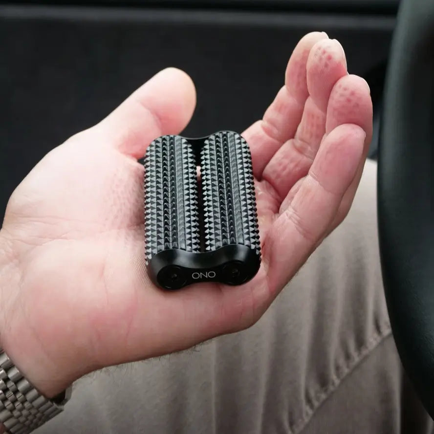 A hand with acupressure imprints holds the full size Ono Aluminum  Acupressure Roller.