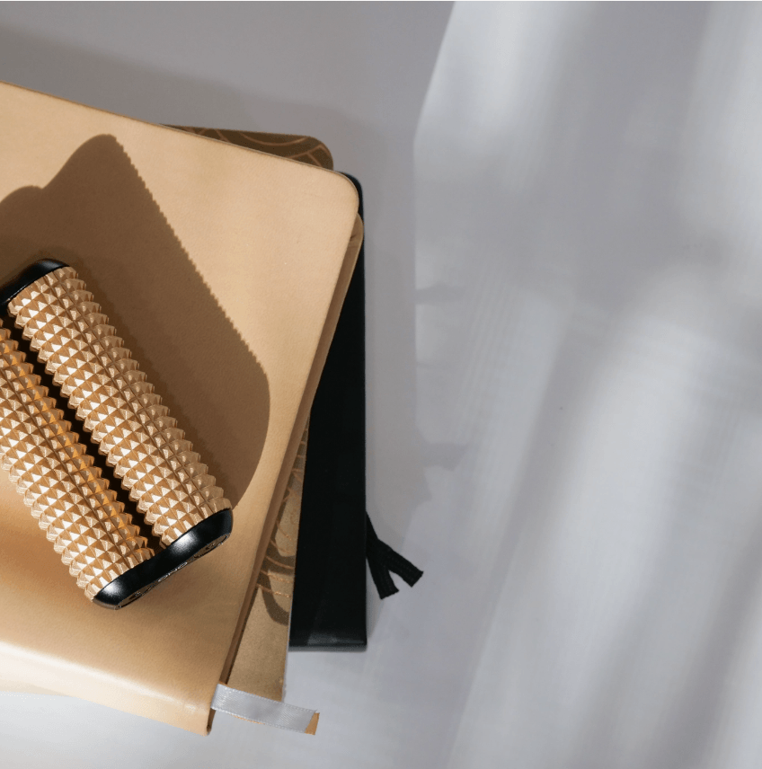 The PeachONO Aluminum Acupressure Roller lays on a stack of leather bound books.