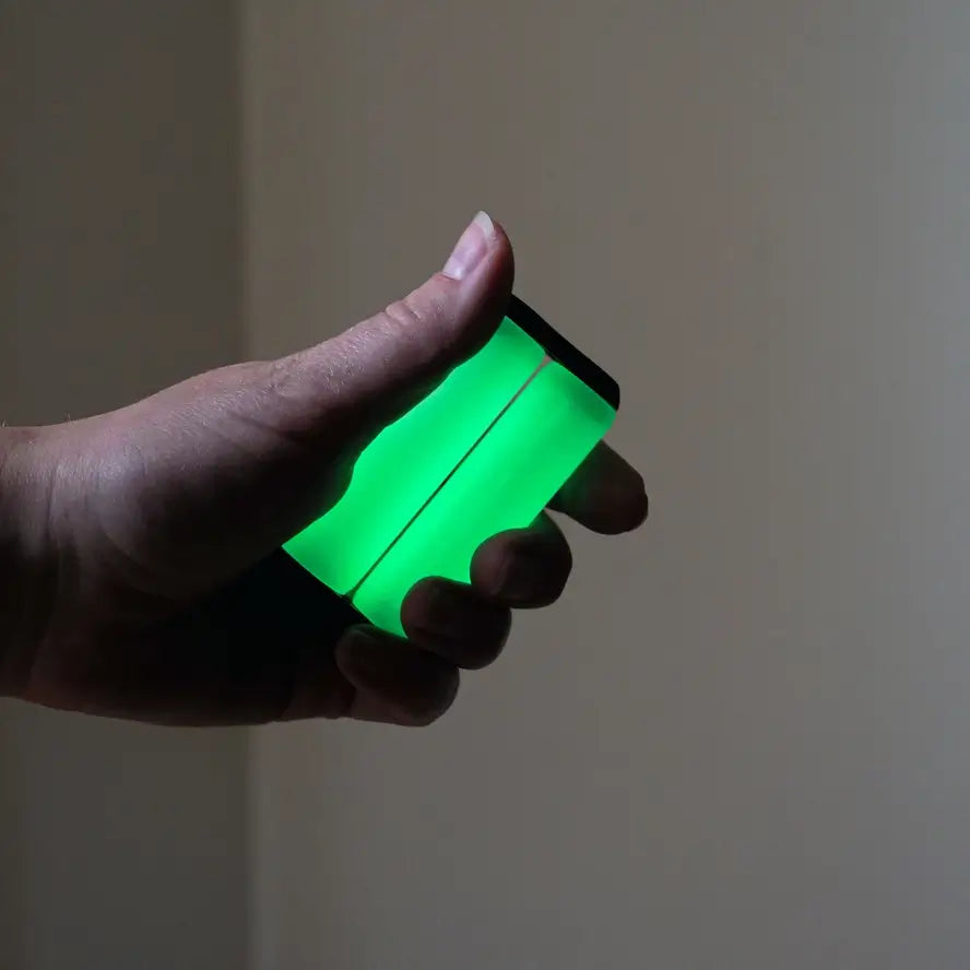 A hand holds the Ono Roller Glow-in-the-Dark junior size while it is glowing.