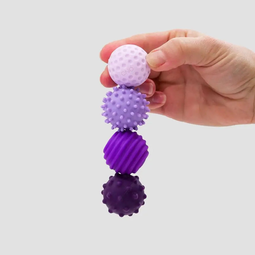 A hand holds the four lavender ONO Roller Signets connected in a straight line.