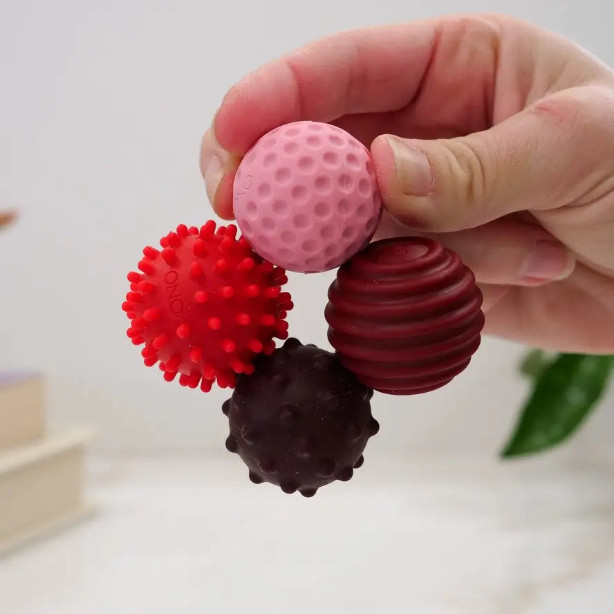 A hand holds four ruby ONO Roller Signets while connected in a circle.