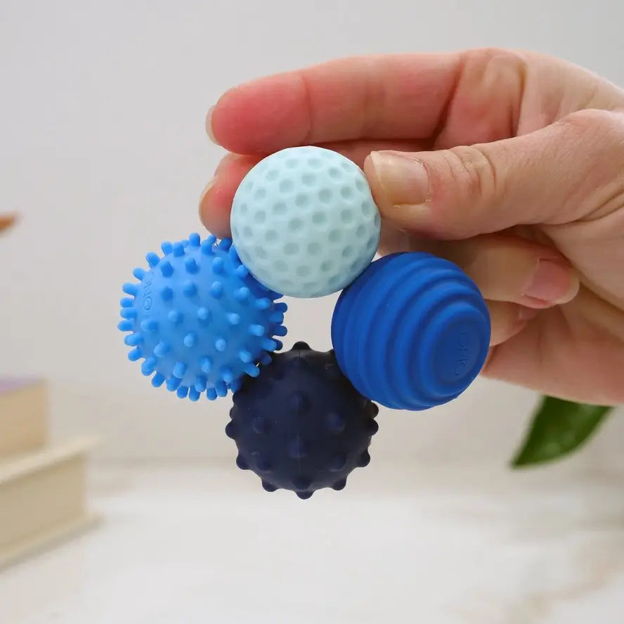 A hand holds the four sapphire ONO Roller Signets while connected in a circle.