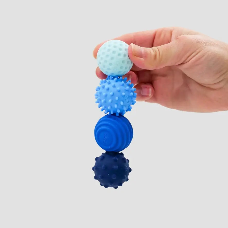 A hand holds the four sapphire ONO Roller Signets while connected in a straight line.