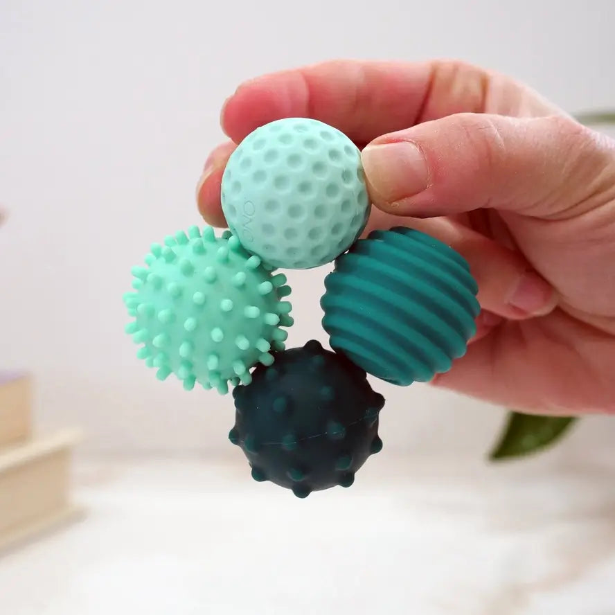 A hand holds four turquoise ONO Roller Signets connected together.