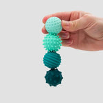A hand holds four turquoise ONO Roller Signets connected and hanging in a line.