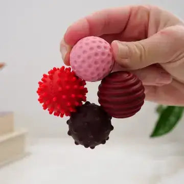 A hand holds one each of the ONO Roller Signets - Ruby 8-Pack to show the four different colors and textures.
