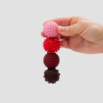 A hand holds the four different colors and textures of the ONO Roller Signets - Ruby 8-Pack.