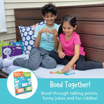 Two children smile as they look through the Let's Chat Portable Conversation Game.