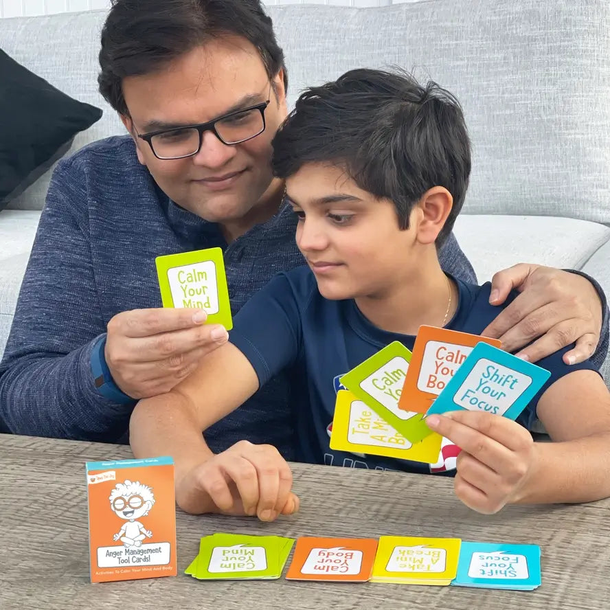 An adult has a hand on a child's shoulder while they review the Anger Management Tool Cards.