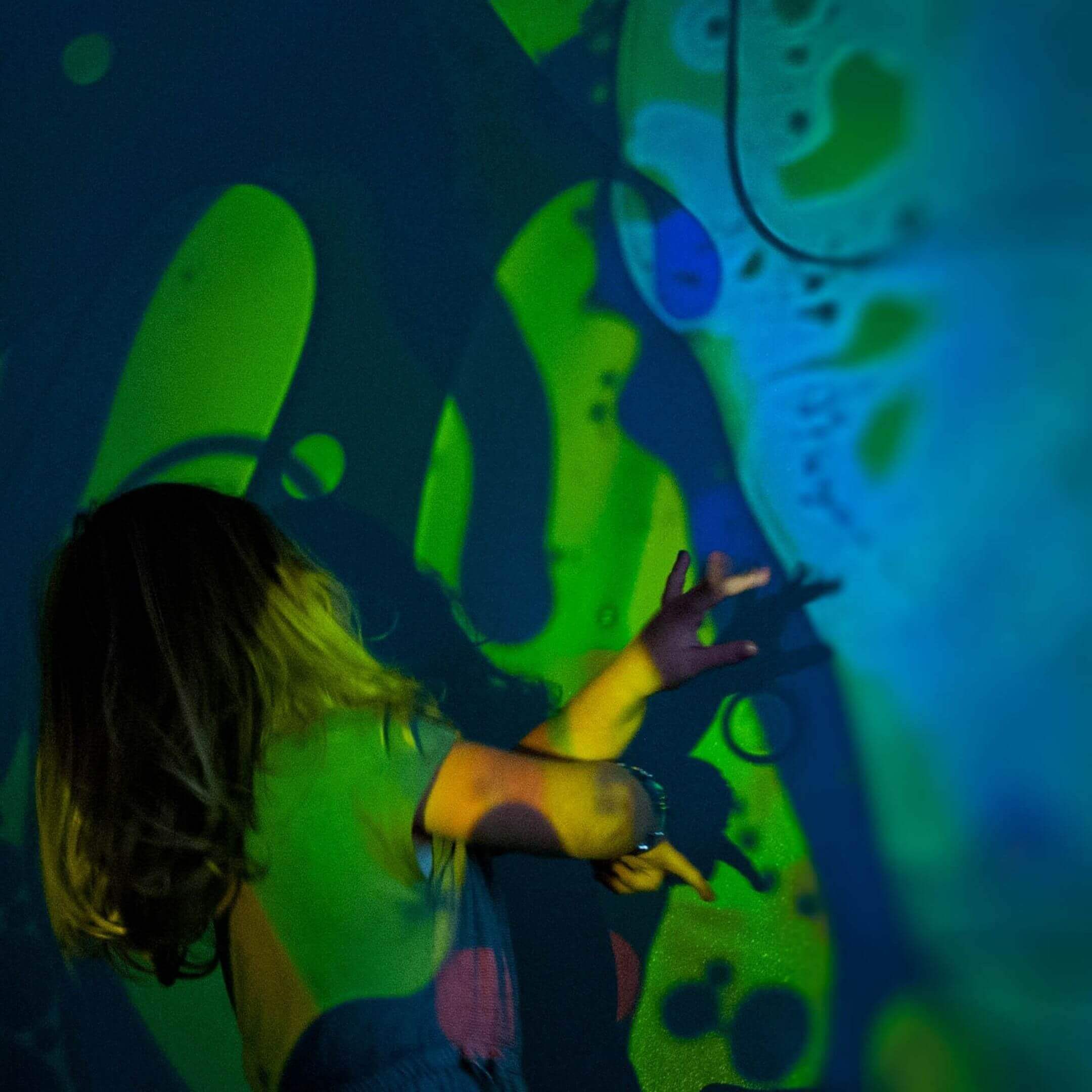 A child plays with the projected image from the Aura Sensory Light Projector.