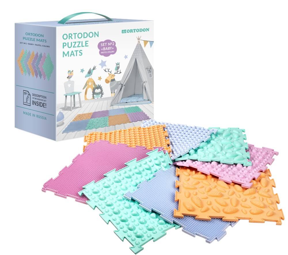 The product box for Ortodon Puzzle Mats in front of the 8 different pastel mats arranged in a pinwheel formation.