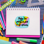 The Give it My Almost 3" Glittery Vinyl Sticker on a piece of grid paper surrounded by colorful desktop items.
