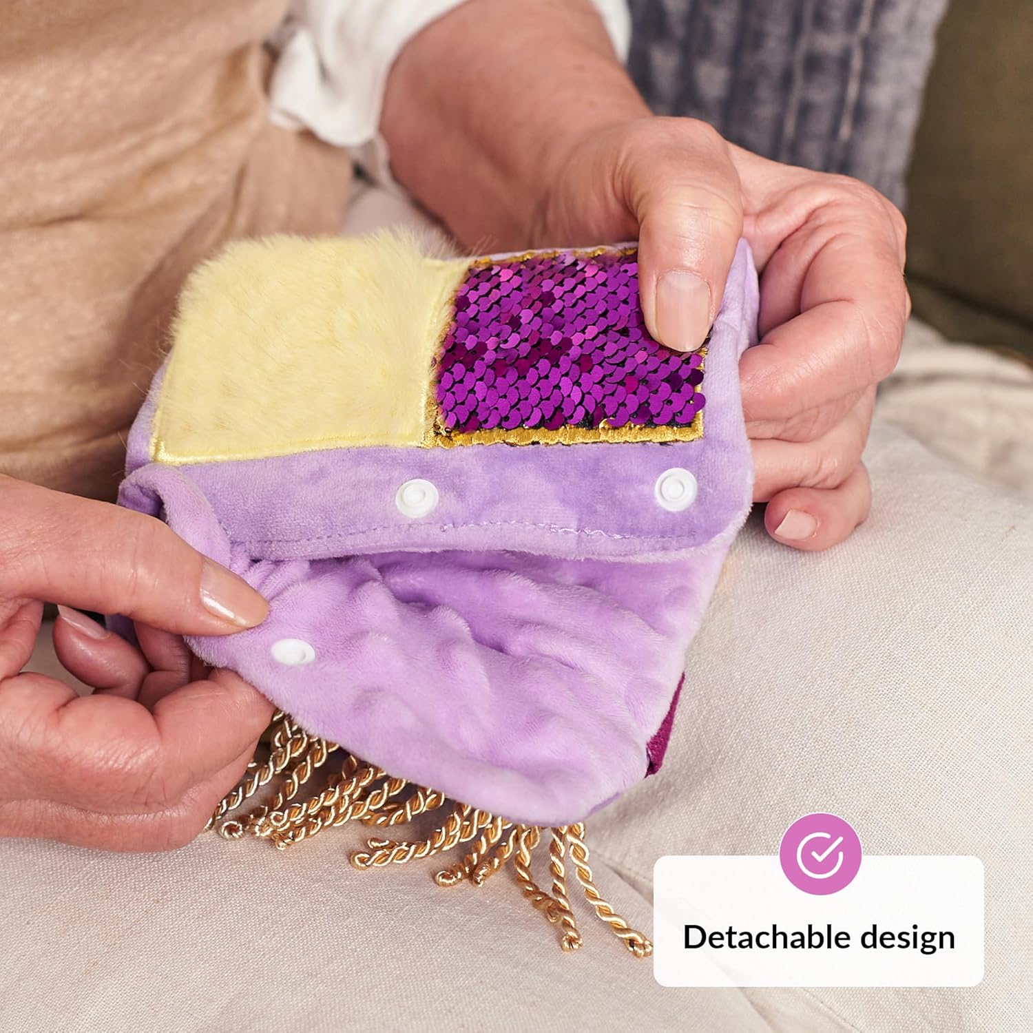 Two hands hold up the Purple Fidget Wrist Cuff and demonstrate the button snaps.