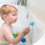 A child in the tub pulls on the suction cup part of the Quut Beedi Fish Lacing Beads.