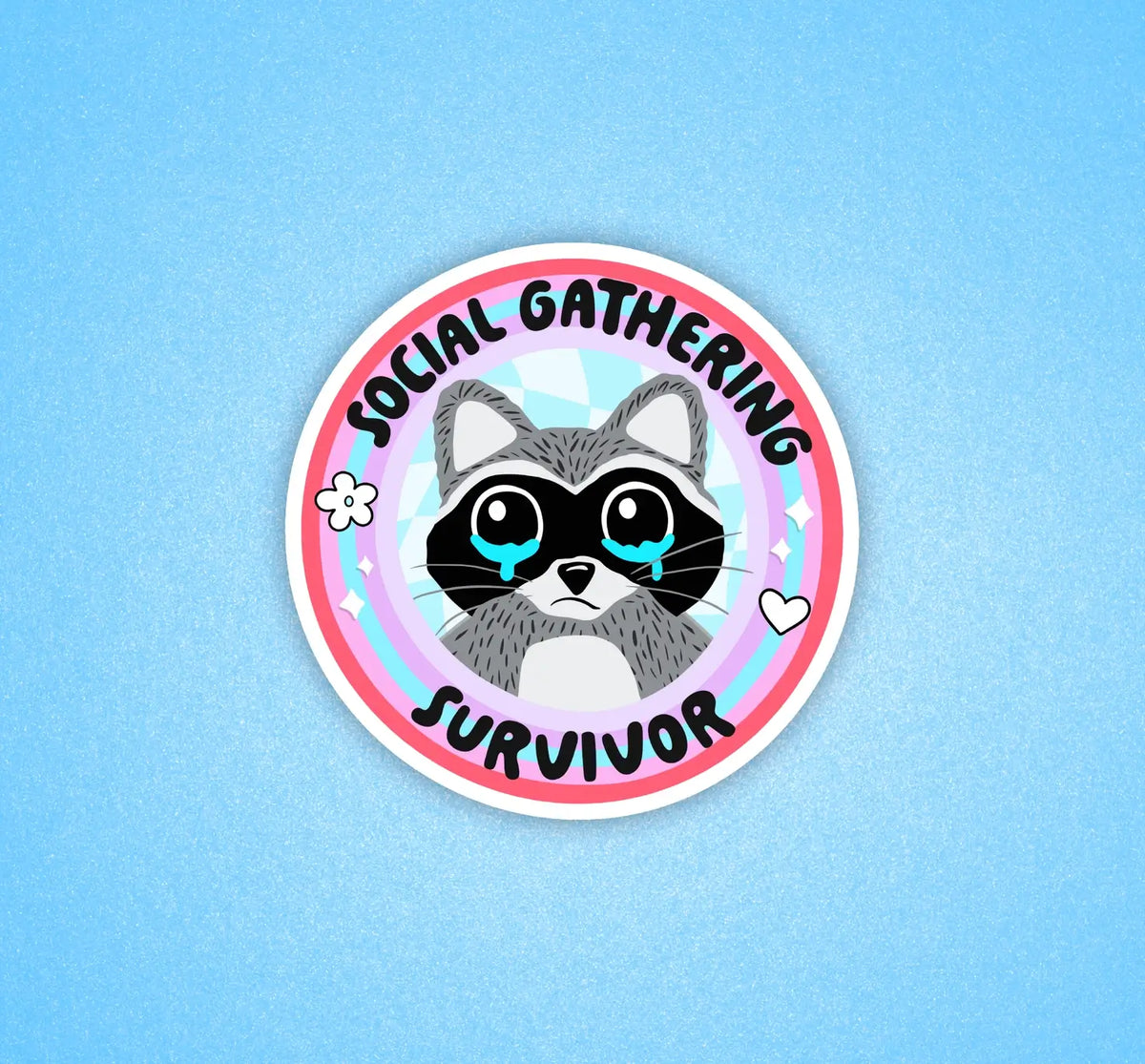 A circular sticker that has a raccoon with teary eyes. The text reads: Social Gathering Survivor.