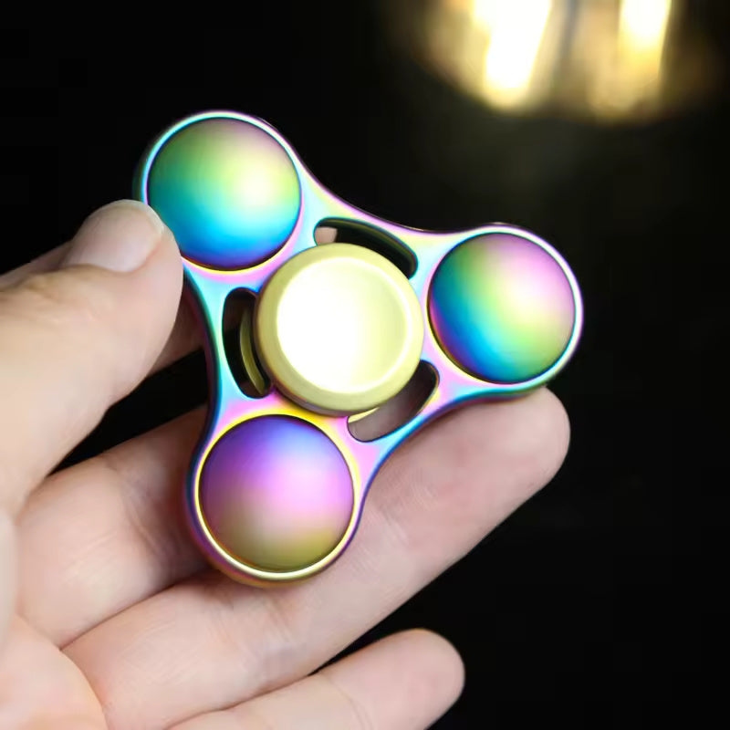 A hand holds the Rainbow Metal Fidget Spinner.