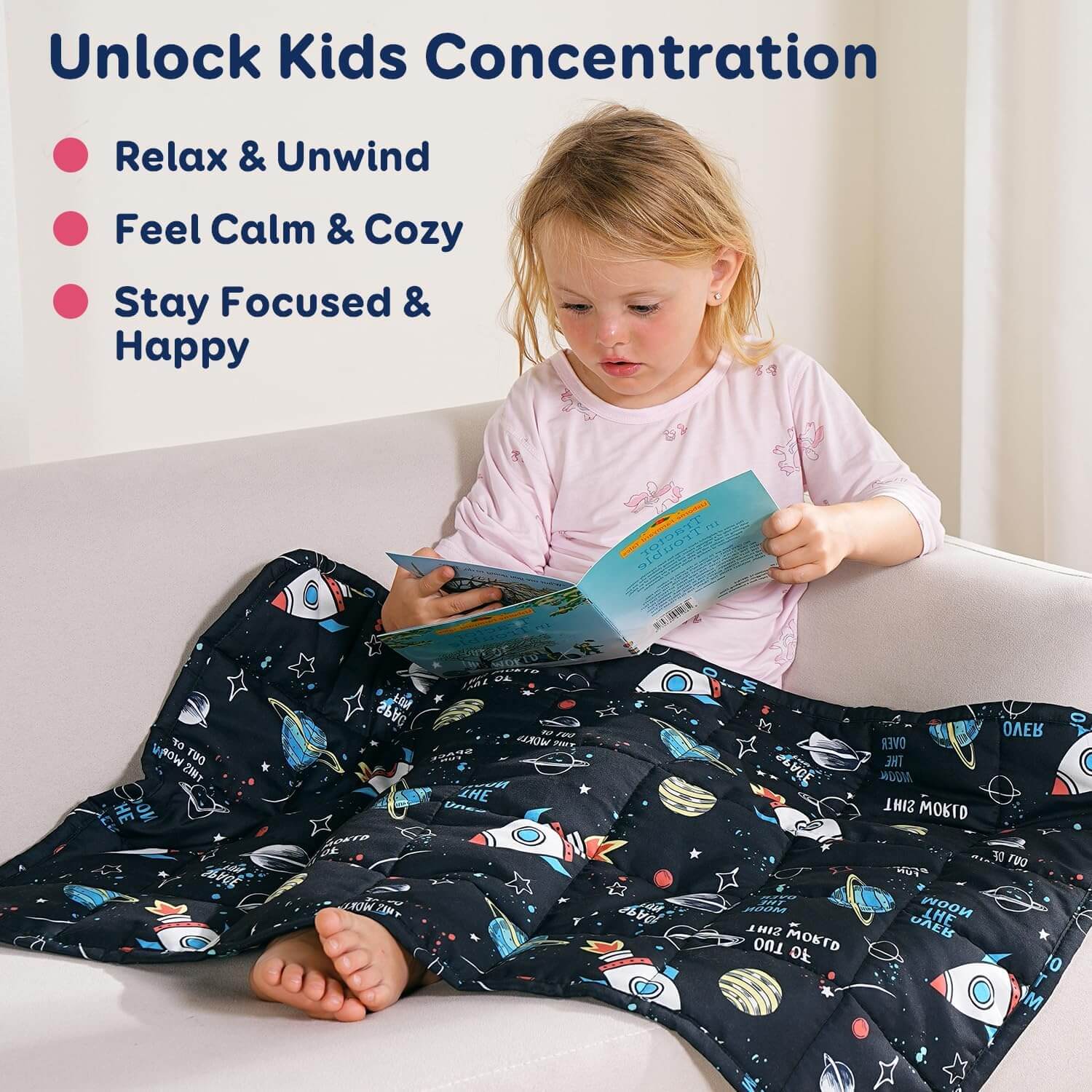 A child leans back on a couch and reads while covered by the Rocket Weighted Cooling Lap Pad 2 lb.