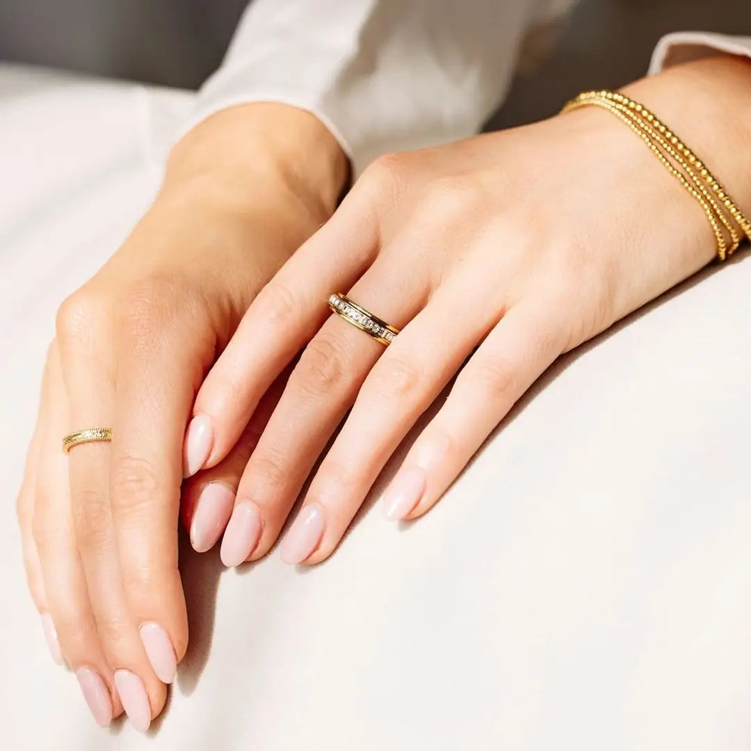 A hand models the Mint & Lily Rose Gold Crystal Statement Spinning Fidget Ring.