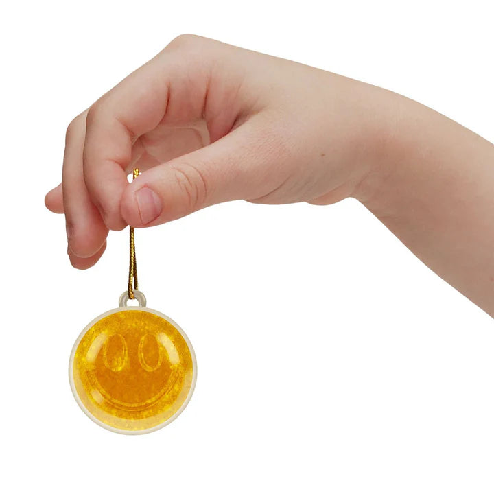 A hand holds a golden glittery squisy orb from the Nee Doh Squishmas 2025 Advent Calendar.