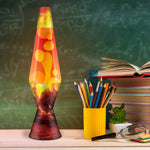 The Erupting Crater Lava Lamp next to a yellow cup holding color pencils and a stack of books.