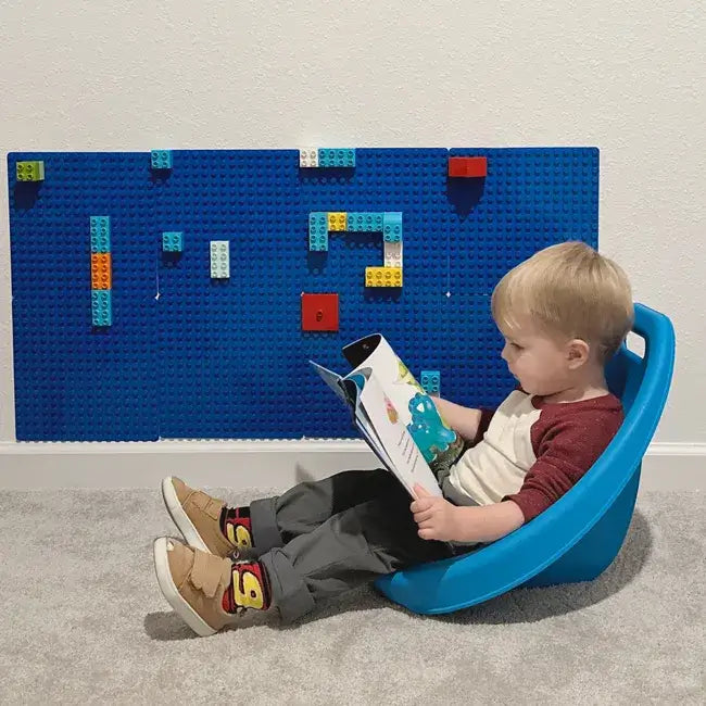 A child sits in the blue Scoop Floor Rocker.