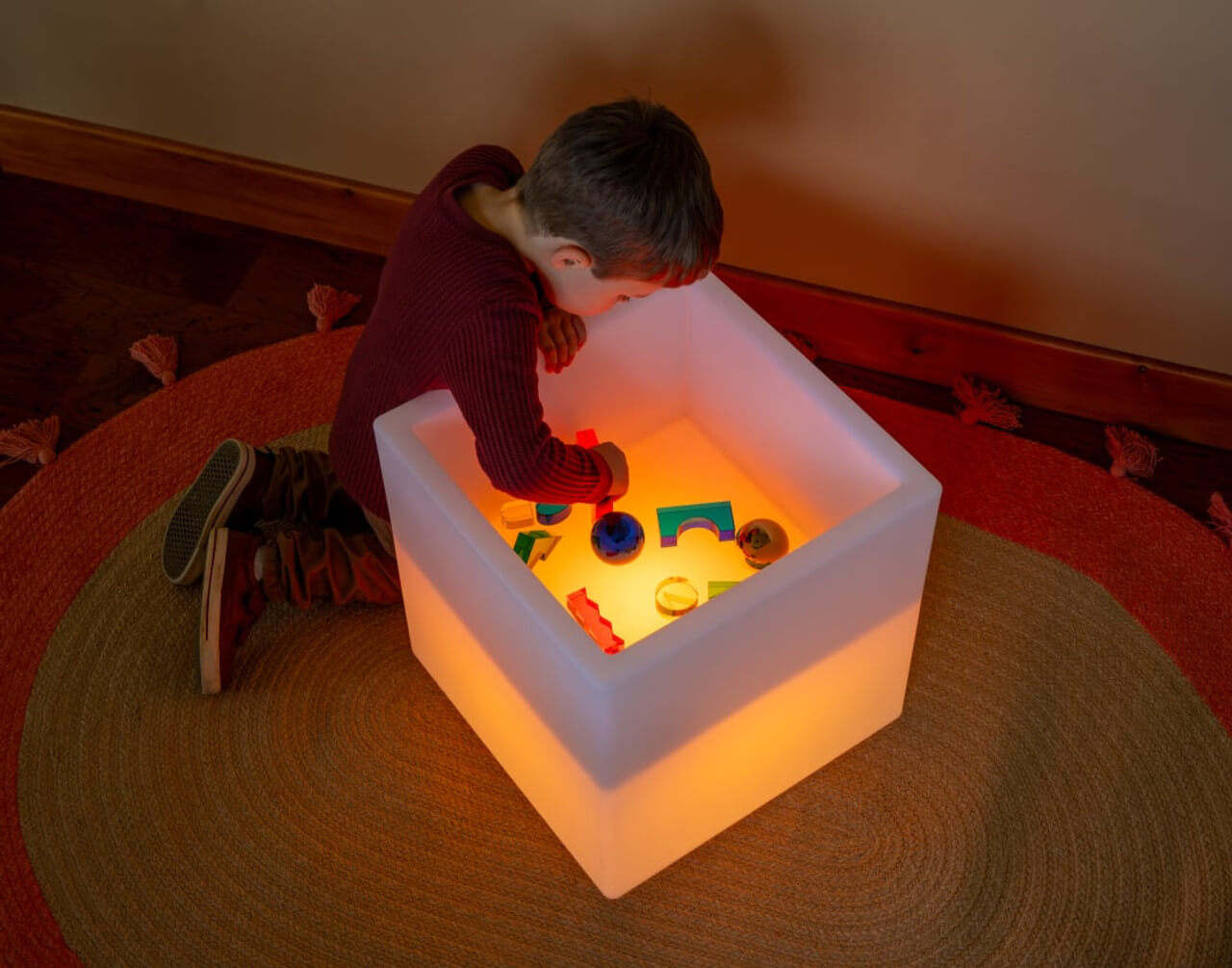 A child leans over the Sensory Mood Play Cube Activity Table.