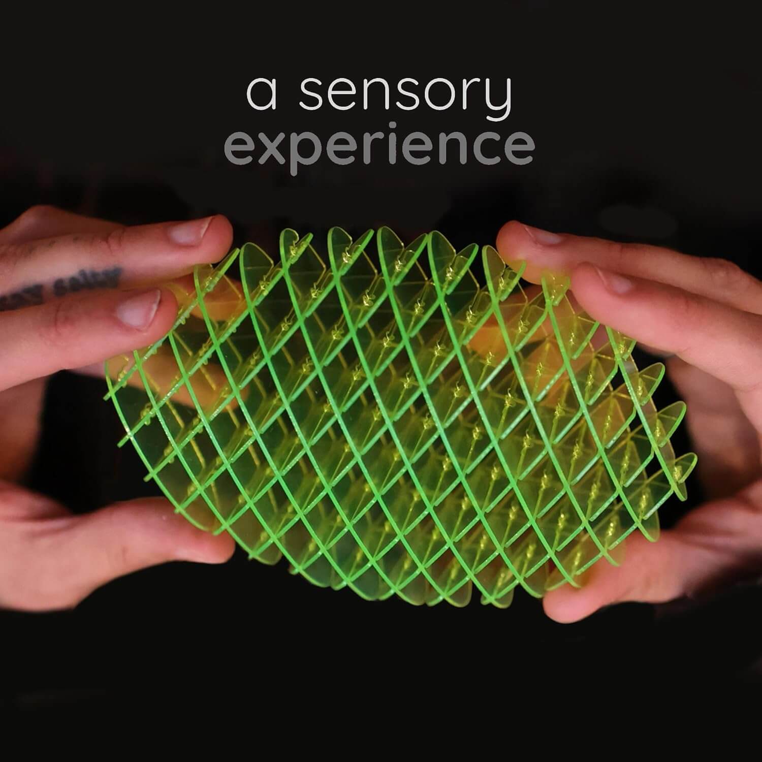 Two hands hold up the Small Green Morf Fidget Worm.