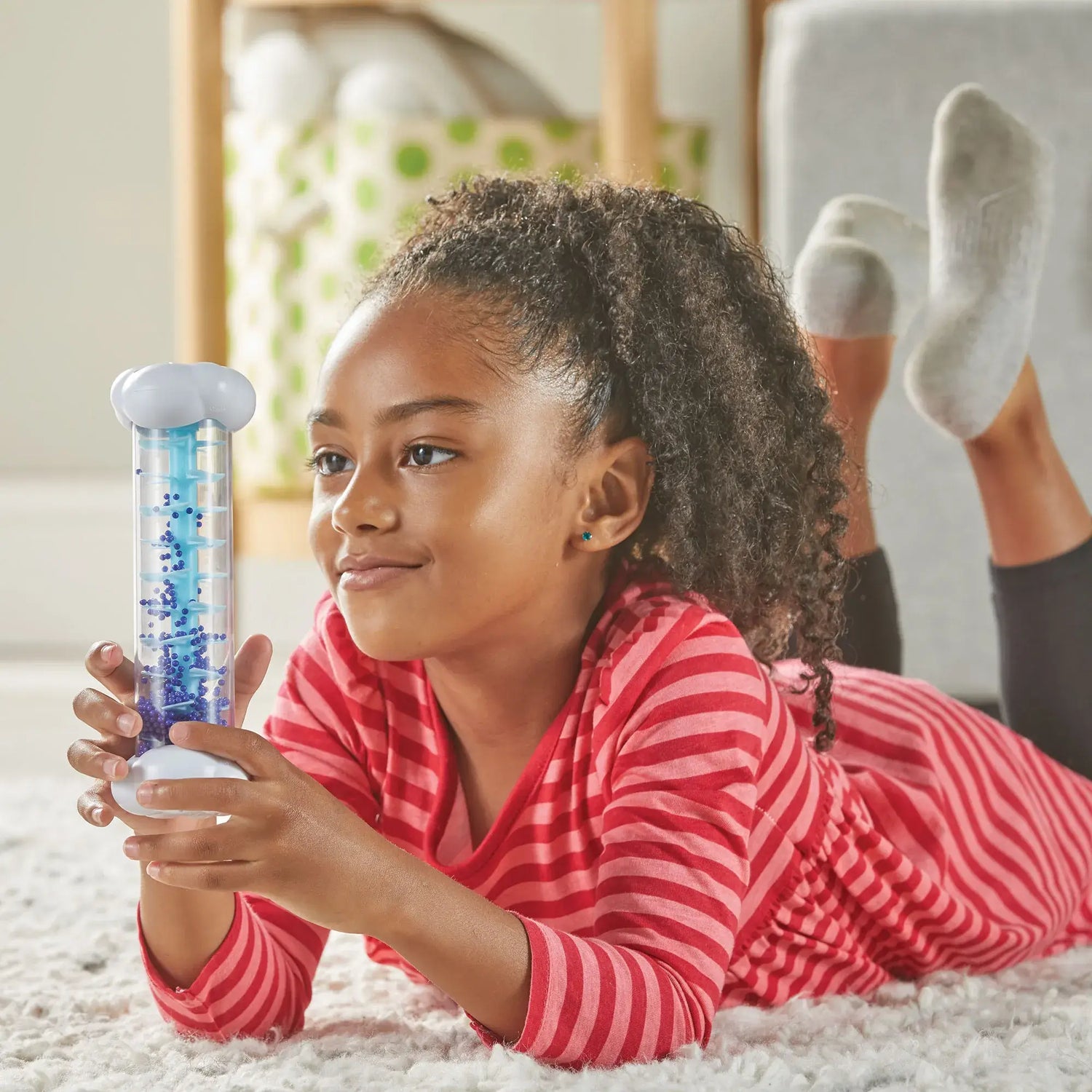 A child holds onto the Drizzle Sounds of Rain Sensory Tube.