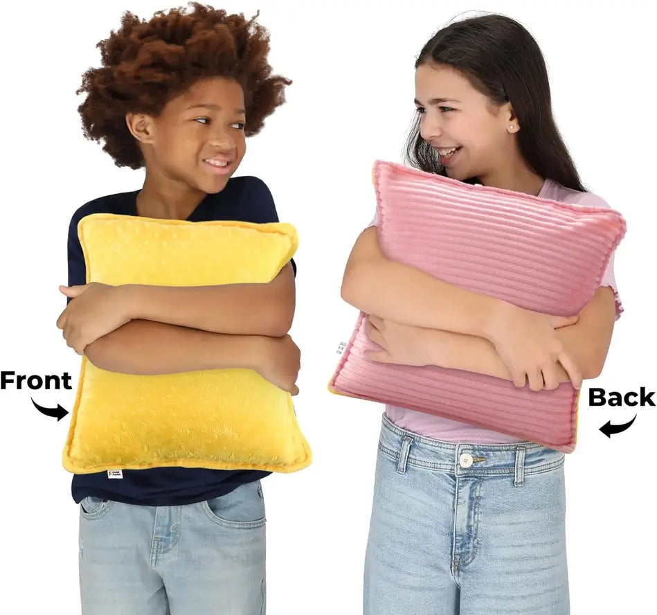 Two children squeeze the Vibrating Pillow, revealing the two different textured and colored sides.
