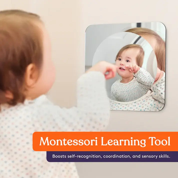 A toddler points at their reflection in the Sensory Bubble Wall Mirror.
