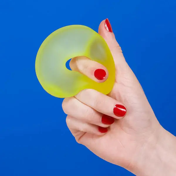 A hand squeezes the Speks Gump Loop Gel Stress Ball.